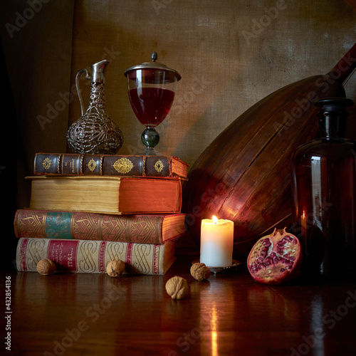 Fotografia jak malarstwo olejne przedstawiająca martwą naturę ze starymi książkami, kieliszkiem czerwonego wina, lutnią gitarową i owocem granatu w stylu starych mistrzów malarstwa holenderkiego.