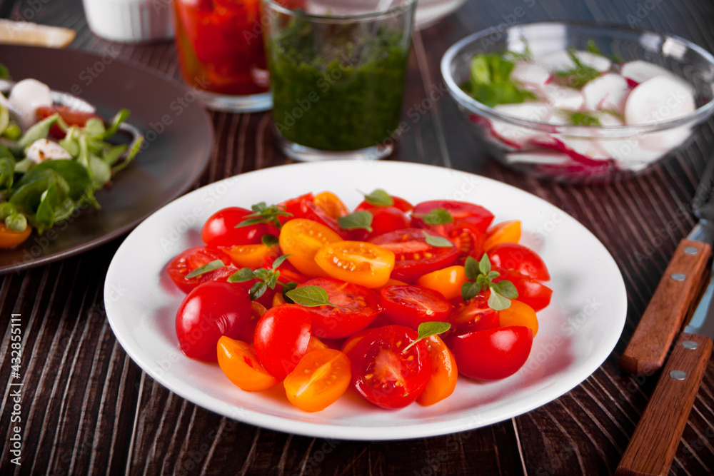 salad of fresh cherry tomatoes with basil on the dinner table salad of fresh cherry tomatoes with basil on the dinner table
