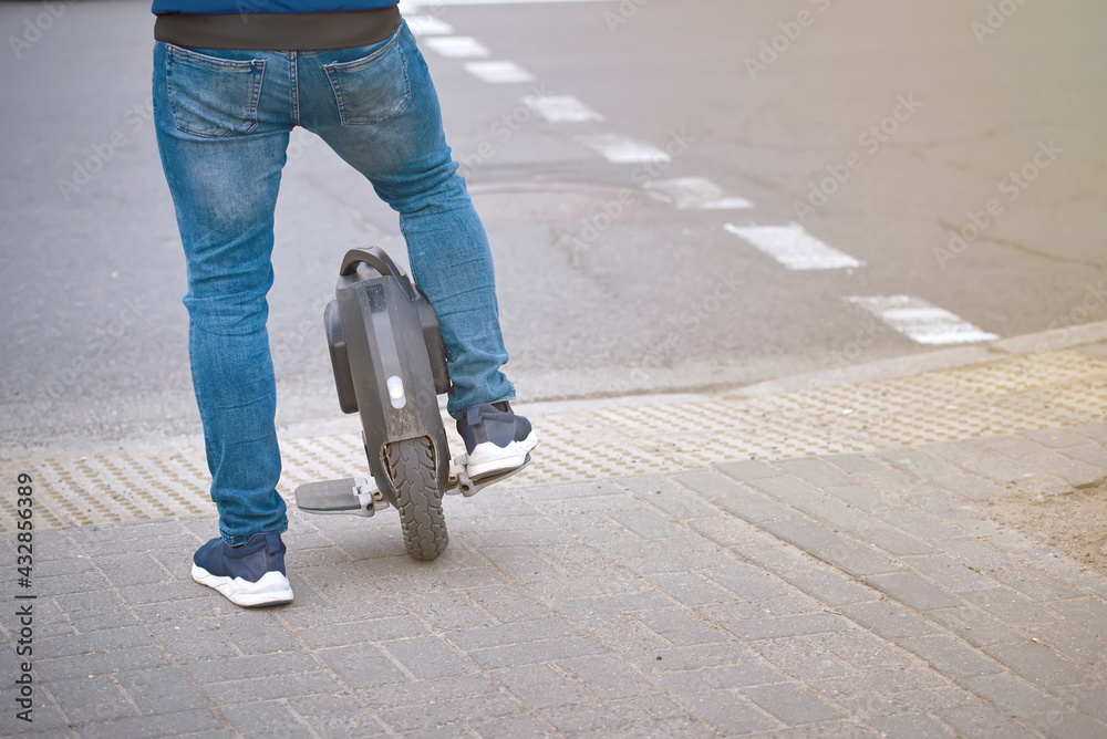 Stockfoto Electric unicycle, man in jeans and sneakers commuting to work on monowheel. Portable
