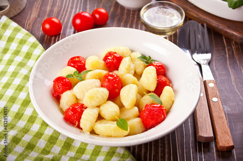 Homemade Italian gnocchi with tomato cherry on the wooden table