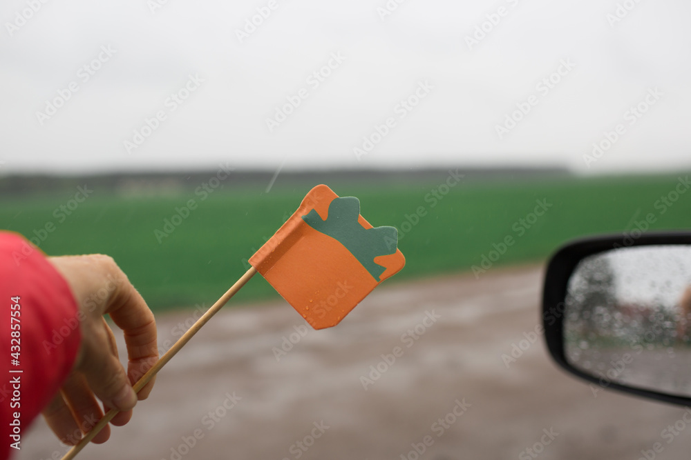 Orange gift from the car window. Mirror with rain drops and a gift from paper in the rain Orange gift from the car window. Mirror with rain drops and a gift from paper in the rain