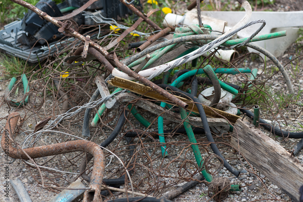heap of scrap metal, rusty wires, old garden hoses and other debris in an urban context, cloudy sky heap of scrap metal, rusty wires, old garden hoses and other debris in an urban context, cloudy sky