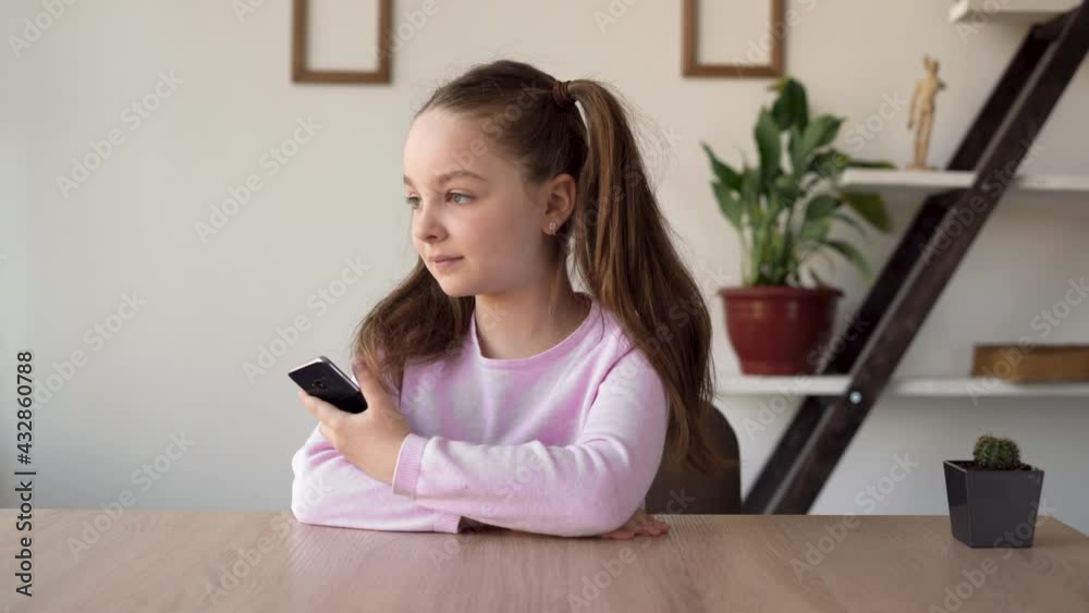 A girl addicted to the Internet sits in a room with a phone in her hands and is bored and waits for a call from her mother. Gadgets in the lives of children and the problems studying online. A girl addicted to the Internet sits in a room with a phone in her hands and is bored and waits for a call from her mother. Gadgets in the lives of children and the problems studying online.