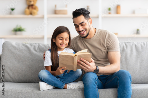 Father and daughter reading book spending time together at home