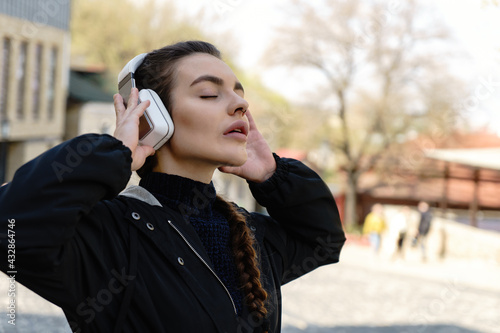 Music in her soul. Urban female portrait. Beautiful young woman listening musig with headsets photo