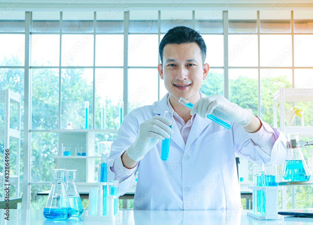 Asian scientists or chemists experiment with droplets of blue liquid chemicals in a laboratory. Asian scientists or chemists experiment with droplets of blue liquid chemicals in a laboratory.