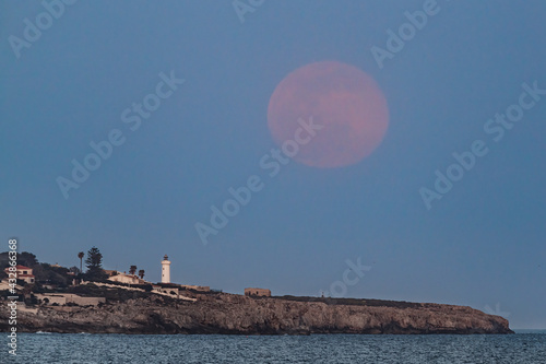 The dawn of the full moon above the Capo Murro di Porco lighthouse.
