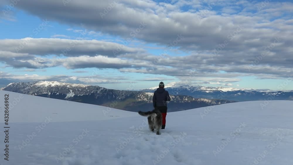 Hiker and dog enjoying the mountain view in winter season Hiker and dog enjoying the mountain view in winter season