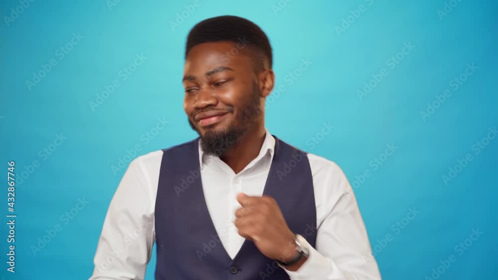 Pleased african man in shirt dancing against blue background Pleased african man in shirt dancing against blue background
