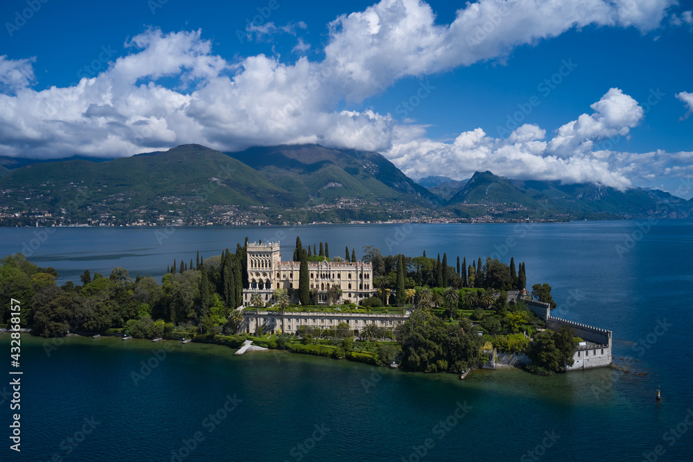 Magnificent aerial panorama of Isola del Garda, Lake Garda, Italy. An island surrounded by the Italian Alps. Isola del Garda, Italy. Castle on an island in Italy. Historic sites on Lake Garda.