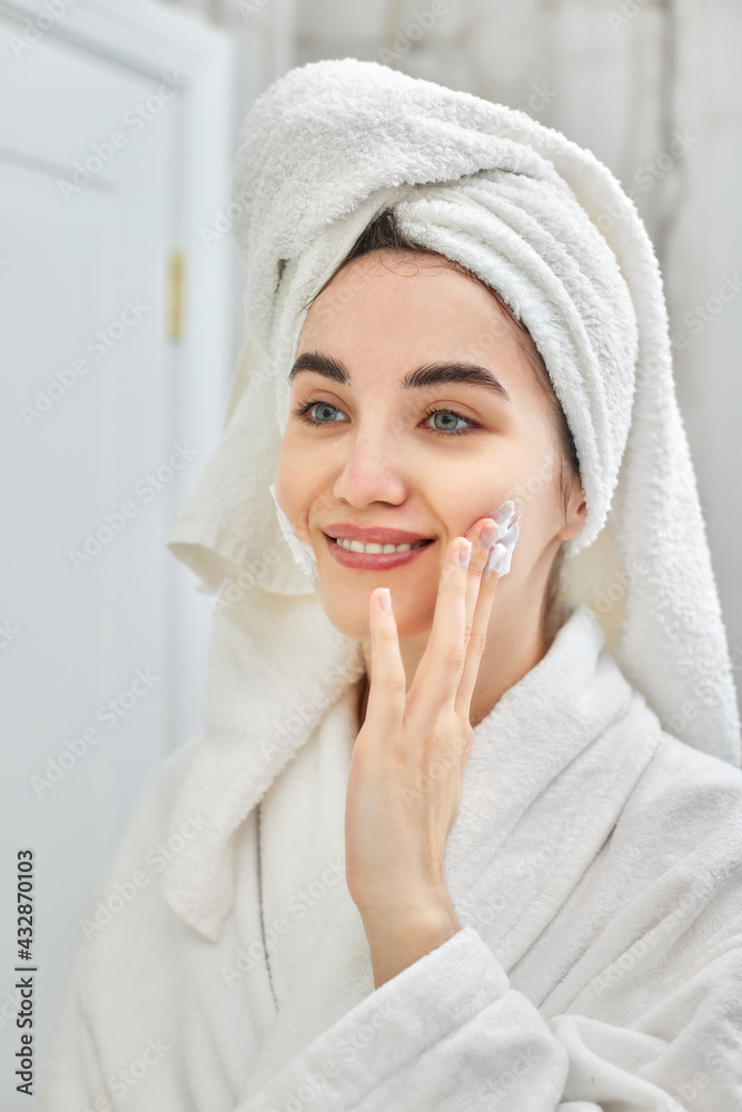 woman in white bathrobes applying apply facial cream woman in white bathrobes applying apply facial cream