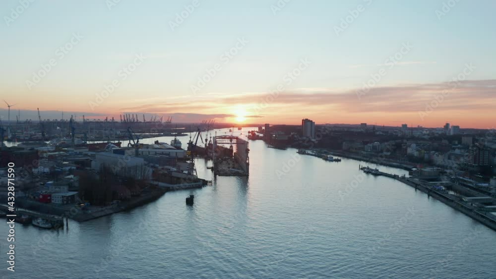 Warehouses in industrial district of Hamburg harbor with cargo port in the distance during sunset Warehouses in industrial district of Hamburg harbor with cargo port in the distance during sunset