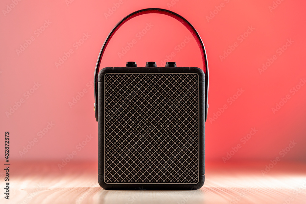Black bluetooth loudspeaker on a reddish background