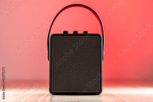 Obraz na płótnie Black bluetooth loudspeaker on a reddish background w salonie