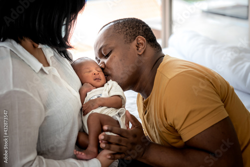 Fototapeta An African American father kissing face, his 12-day-old baby black skin newborn