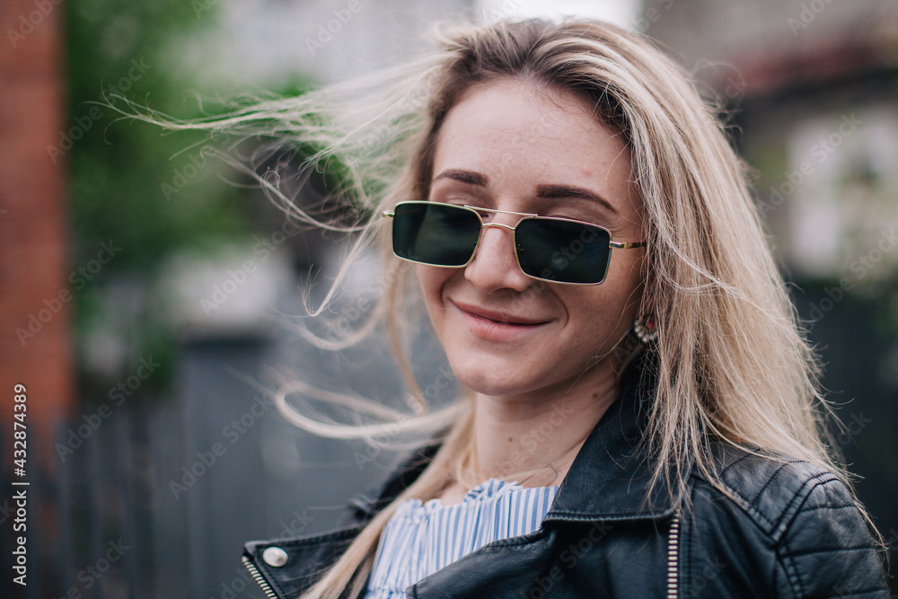 Young blonde in leather jacket and sunglasses posing in the street Young blonde in leather jacket and sunglasses posing in the street