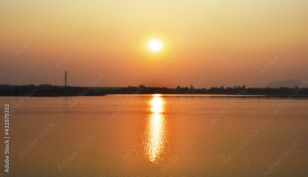 Sunset captured near a lake with yellowish reflection in water.