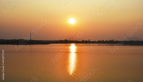 Sunset captured near a lake with yellowish reflection in water.