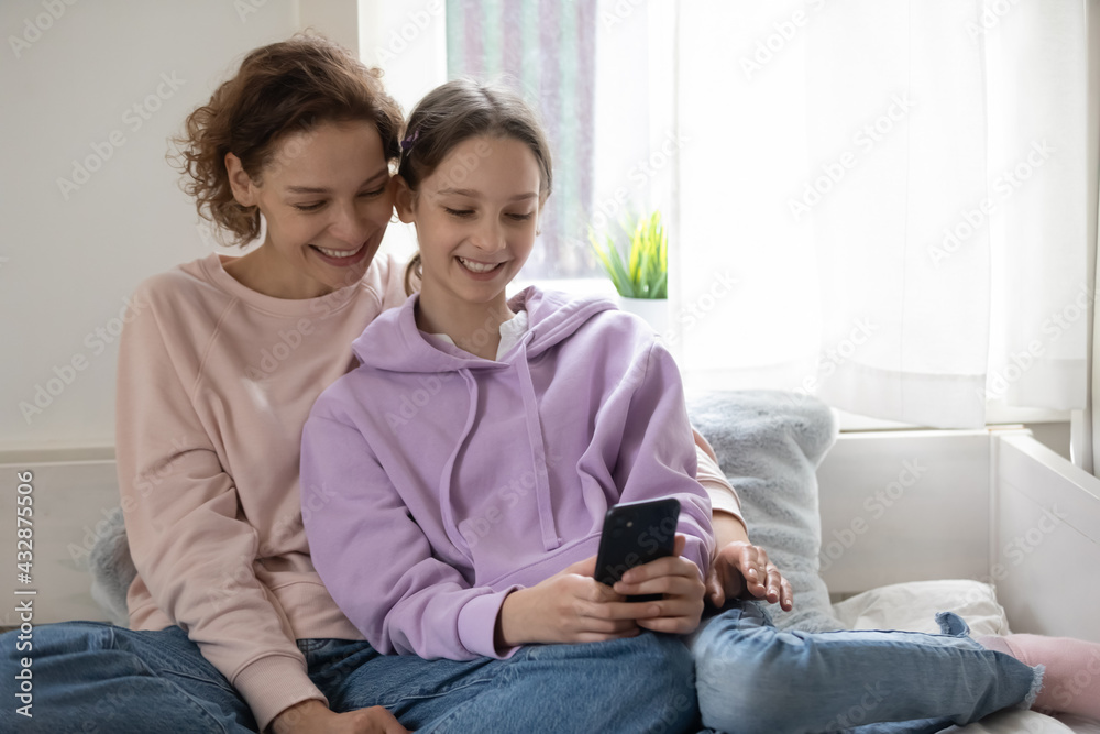 Smiling happy different female generation family resting on comfortable sofa, using software smartphone applications, playing mobile game, blogging, web surfing online, watching funny photo video. Smiling happy different female generation family resting on comfortable sofa, using software smartphone applications, playing mobile game, blogging, web surfing online, watching funny photo video.