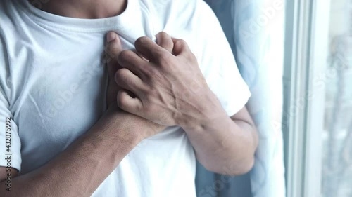 young man suffering pain in heart and holding chest with hand  photo