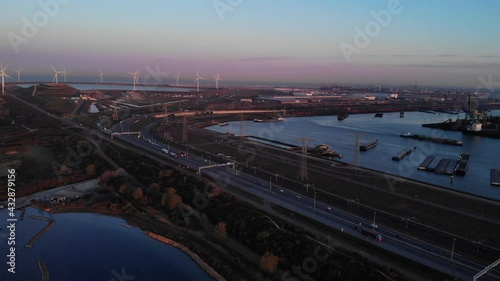 Seaport Of Maasvlakte Along With The Windmills In Rotterdam, Netherlands At Dusk. aerial, pullback photo