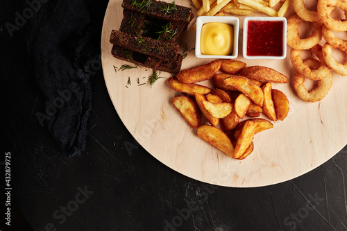 tackler with snacks on black textured background top view photo