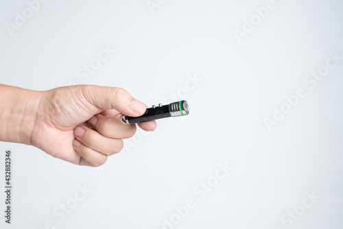 Hand holding small LED flashlight with pointing laser