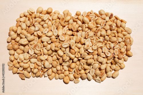 large pile heap display of fresh roasted peanut legume display on a natural wood table surface as a studio food scene