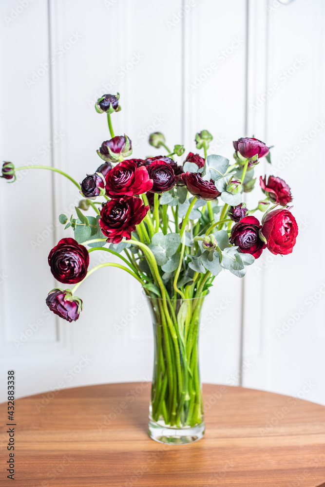 Frühlingsblumenstrauß mit Ranunkeln und Eukalyptus, dunkelrote Blüten Frühlingsblumenstrauß mit Ranunkeln und Eukalyptus, dunkelrote Blüten