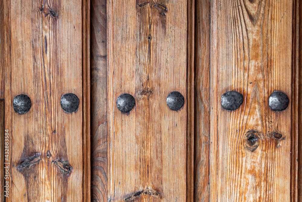 Antique wooden door with nails and knots. Rustic and retro old door full of knots and scratches. Vintage wood texture surface, wood vein. Pareidolia, faces in wood grain. Antique wooden door with nails and knots. Rustic and retro old door full of knots and scratches. Vintage wood texture surface, wood vein. Pareidolia, faces in wood grain.