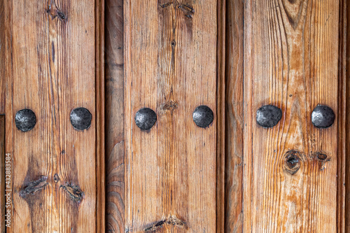 Antique wooden door with nails and knots. Rustic and retro old door full of knots and scratches. Vintage wood texture surface, wood vein. Pareidolia, faces in wood grain.