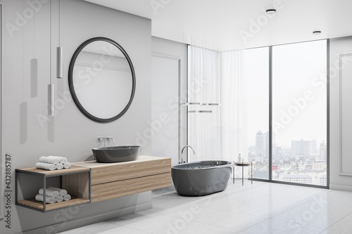 Modern spacious bathroom with city view from bug window  glossy floor  black bath and round mirror over black sink