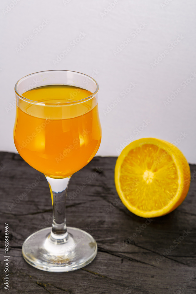 Orange juice in a glass near oranges on a black background.