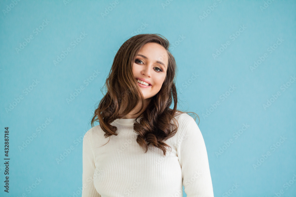 Happy woman in white sweater smiling on blue background