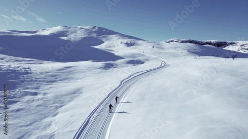 Active couple cross country skiing on a slope through wild snowy mountain wilderness on a clear cold winters day.