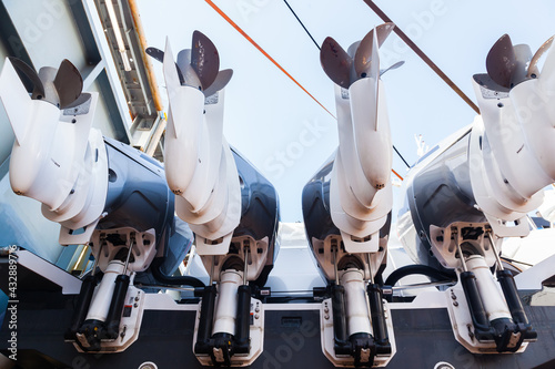 Four outboard outboard motors against the sky, mounted on a boat in dry dock, bottom view.