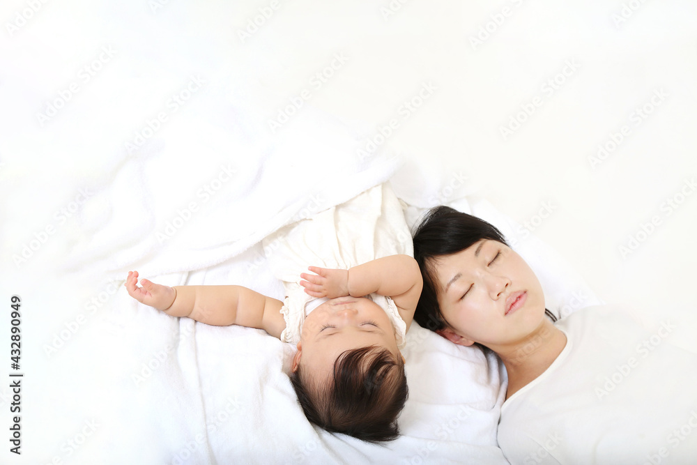 Mom taking a nap with her baby on a background of white sheets Mom taking a nap with her baby on a background of white sheets