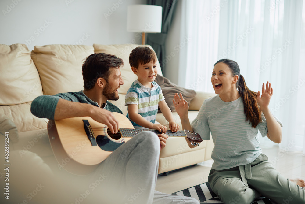 Happy family playing acoustic guitar and having fun at home.