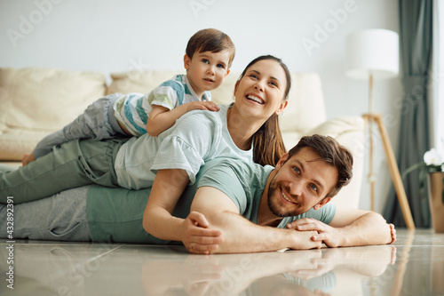 Happy family having fun while making human pyramid on the floor at home.