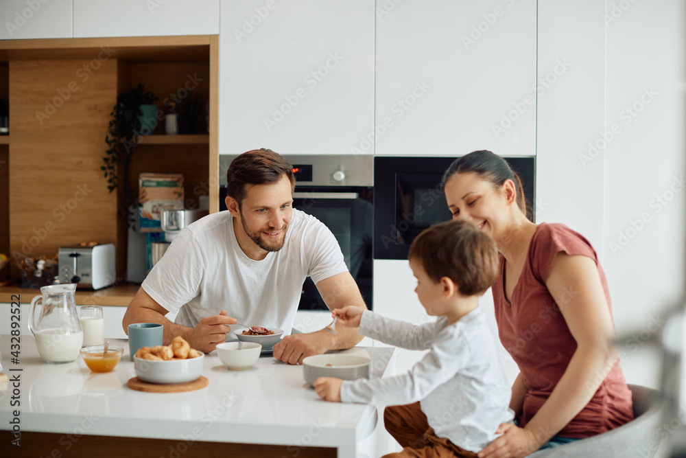 Happy family talking while eating breakfast in the morning at home.