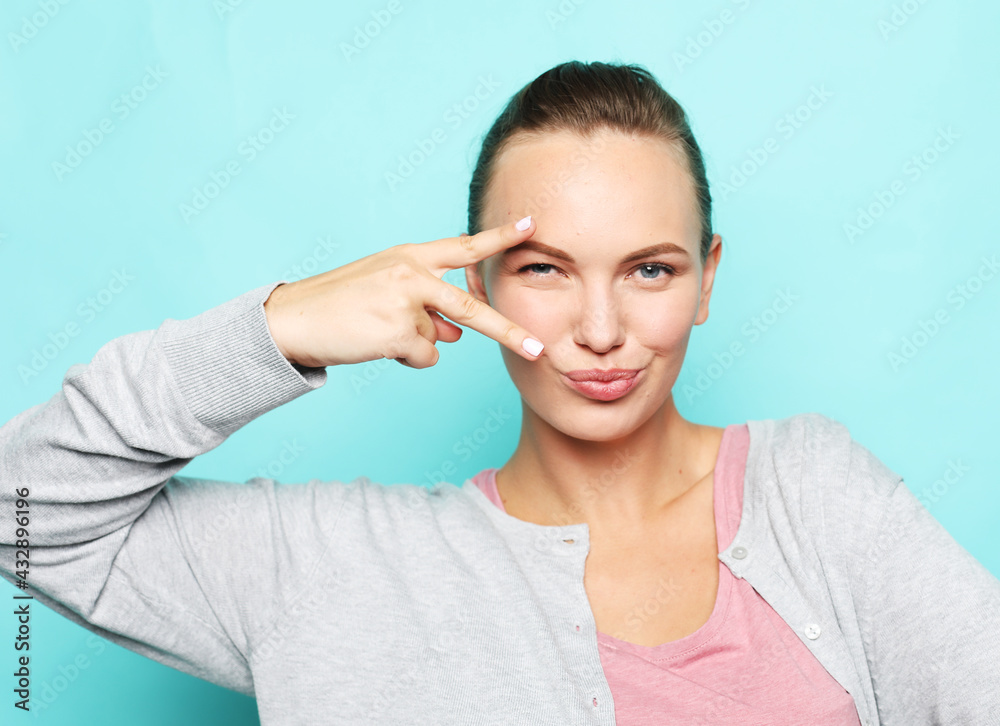 Portrait of a pretty young woman showing the peace sign on blue background. Portrait of a pretty young woman showing the peace sign on blue background.