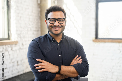 Fototapet Headshot of skilled hindu male employee standing with arms crossed in modern off