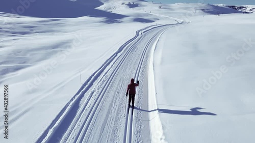 Person  cross country skiing on a slope through wild snowy mountain wilderness on a clear cold winters day.