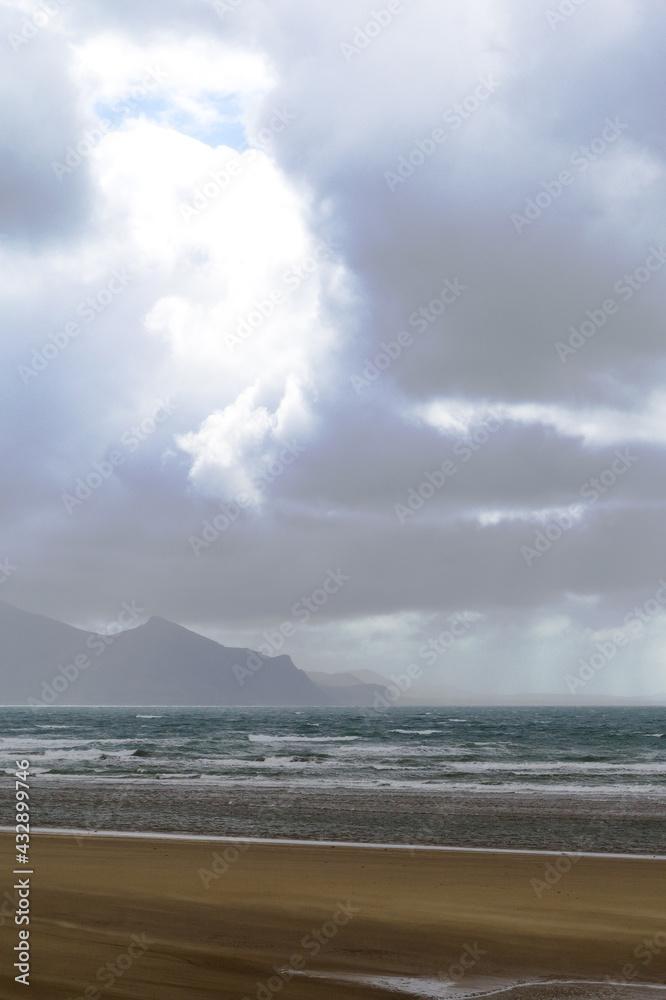 Dinas Dinlle beach north Wales. Dramatic winter landscape over mountains and sea on a stormy winters day. Grey cloudy skies provide copy space.