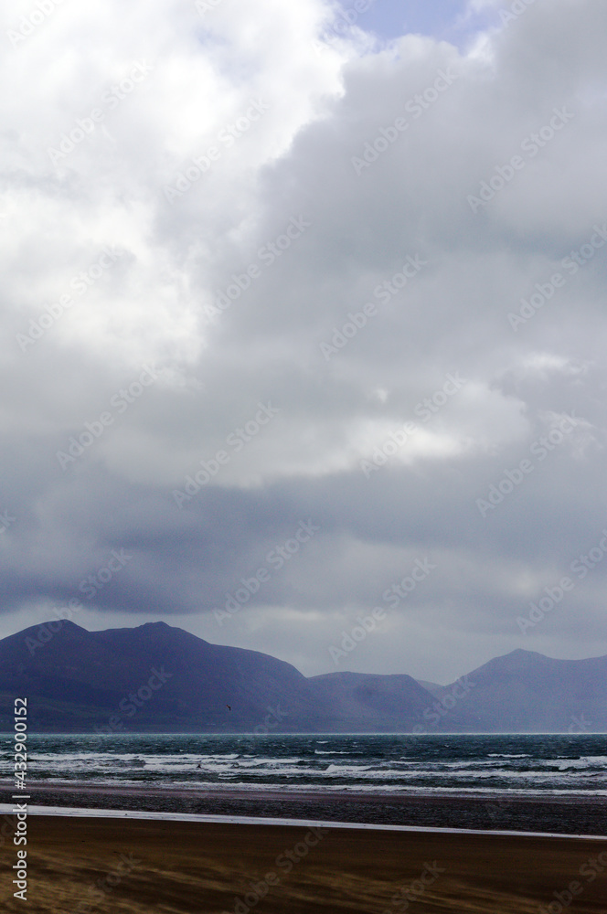 Dinas Dinlle beach north Wales. Dramatic cloudy winter landscape with view over the Llyn peninsula mountains. Sky and sea on a stormy winters day. Grey cloudy skies provide copy space. Dinas Dinlle beach north Wales. Dramatic cloudy winter landscape with view over the Llyn peninsula mountains. Sky and sea on a stormy winters day. Grey cloudy skies provide copy space.