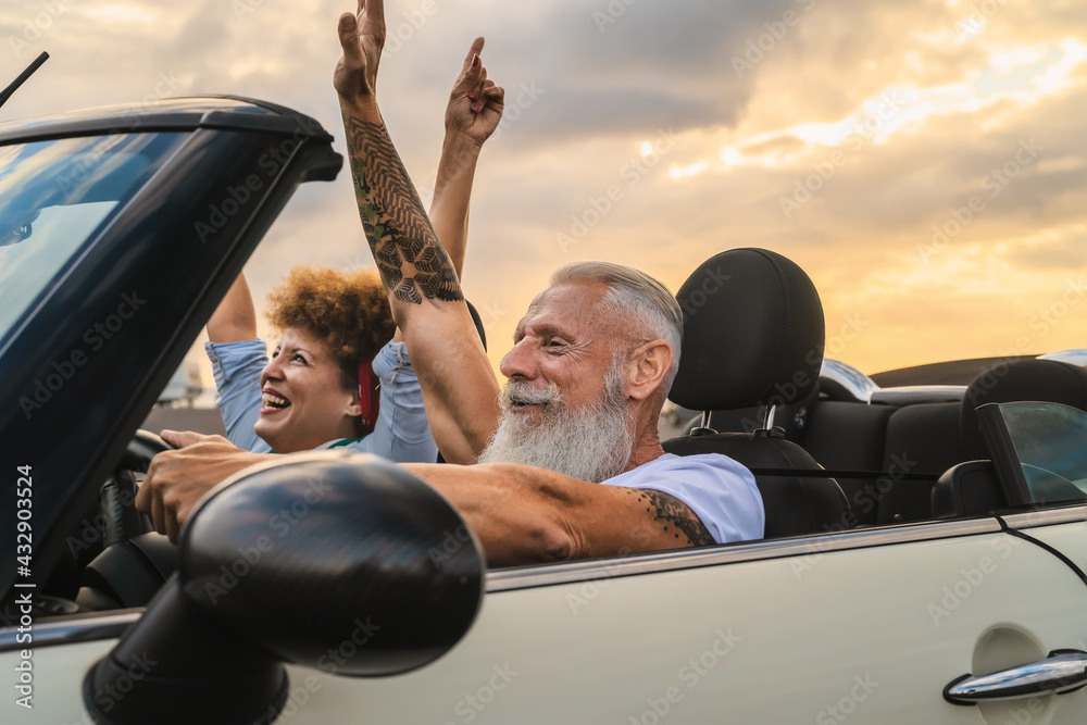 Happy senior couple having fun driving on new convertible car - Mature people enjoying time together during road trip tour vacation - Travel people lifestyle concept - obrazy, fototapety, plakaty 