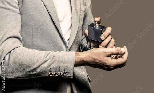 Man holding up bottle of perfume. Fashion cologne bottle. Man perfume, fragrance. Masculine perfume. Perfume or cologne bottle. Male fragrance and perfumery, cosmetics. Copy space