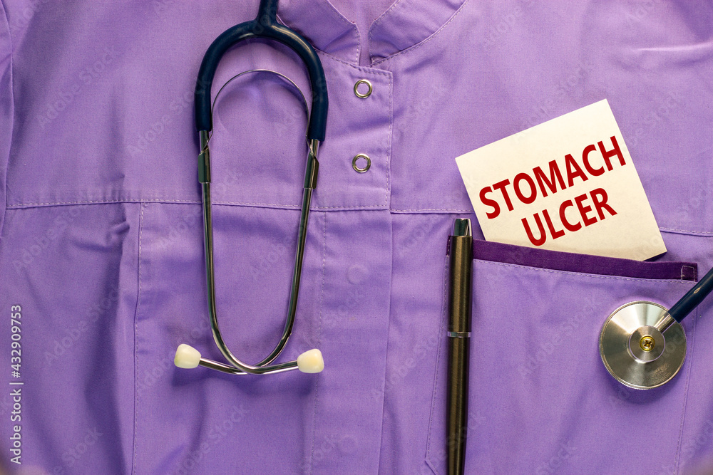 Stomach ulcer symbol. Medical uniform, white card with words 'Stomach ulcer', metalic pen and stethoscope. Medical and stomach ulcer concept. Copy space.