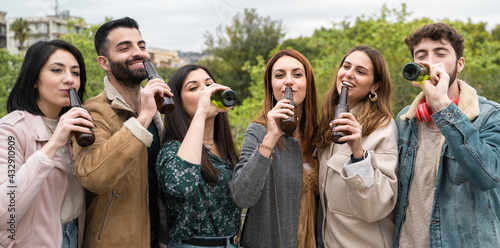 Young people drinking bottled beers in the park. Friends having fun drinking together in the park lifestyle concept.