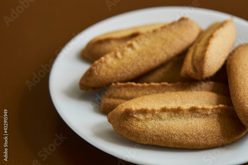 Baked cookies on white plate on brown background